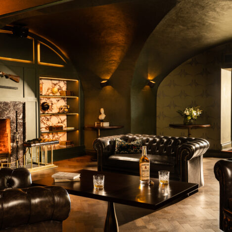 Cosy hotel lounge with leather sofas, a roaring fireplace, and scenic outdoor view.