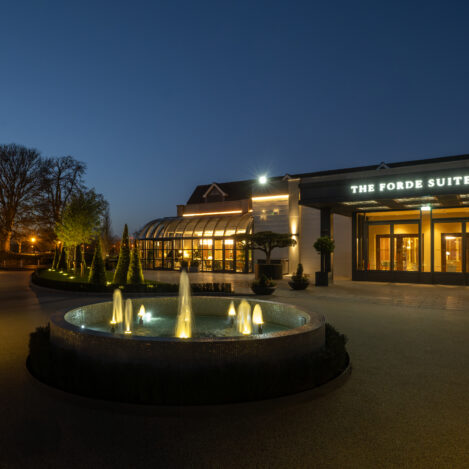 Elegant resort entrance with illuminated fountain, welcoming guests at dusk.