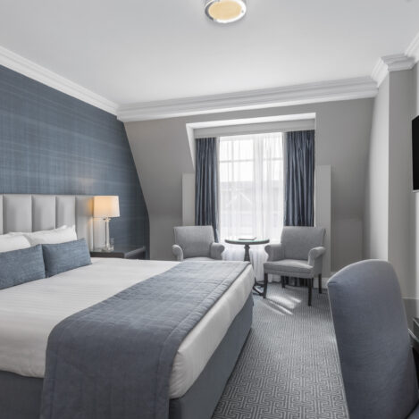 Spacious hotel room with a cosy bed, seating area, and elegant decor.