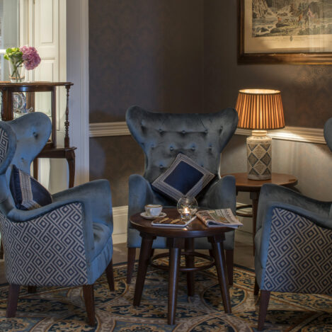 Cosy seating area with elegant armchairs, warm lighting, and a small coffee table in a hotel lounge.
