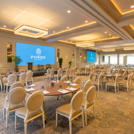 Elegant conference room set for a large gathering, featuring round tables and chic seating at The Forde Suites.
