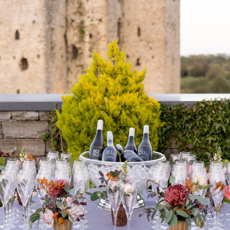 Elegant outdoor table with champagne and flowers, set against a historic stone castle backdrop.