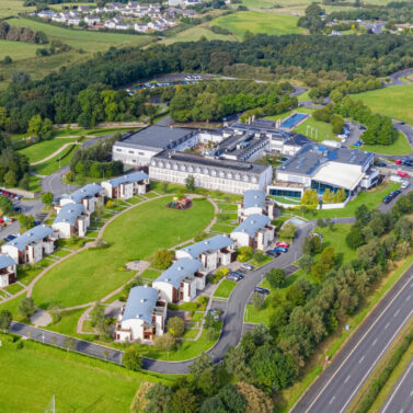 Aerial view of a charming resort surrounded by lush greenery and nearby countryside homes.