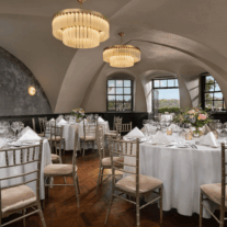 Elegant dining area set for a family celebration with round tables and floral centrepieces.