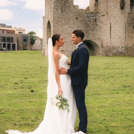 A couple embraces near a historic stone ruin, enjoying a romantic moment outdoors.