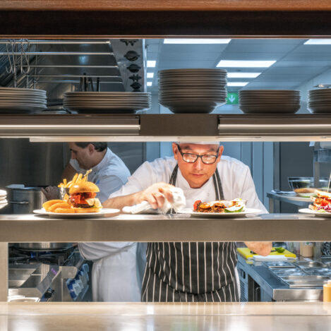 Chef in a bustling kitchen adding final touches to plates, creating a warm, welcoming dining experience.