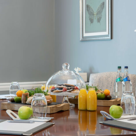 Elegant meeting room with a table set for a group, featuring drinks and fresh fruit.