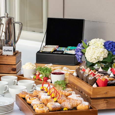 Elegant breakfast buffet with tea, coffee, pastries, and fresh flowers in a cosy setting.