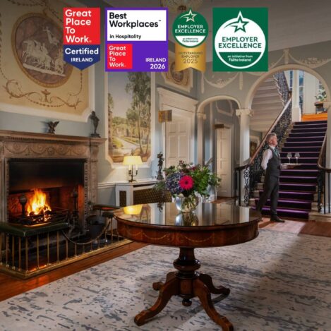 Elegant hotel lobby with a roaring fireplace and a server carrying drinks for guests.