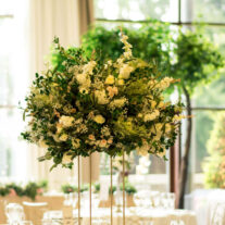 Elegant table setting with lush floral centrepiece in sunlit dining area.