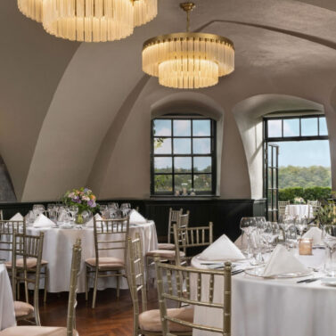 Elegant dining room with round tables set for a family gathering, featuring large windows.