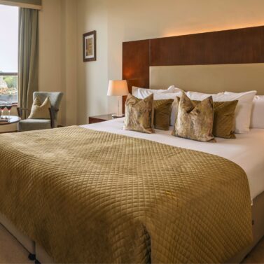 Elegant hotel room with a cosy bed, ambient lighting, and a window view of a stone tower.