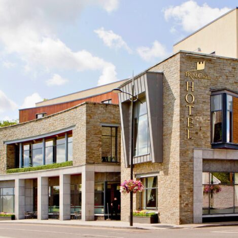 Modern hotel exterior with charming stone facade and large windows, under a clear blue sky.