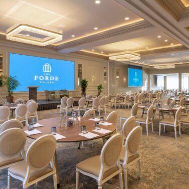 Elegant hotel conference room with round tables, plush seating, and warm lighting at The Forde Suites.