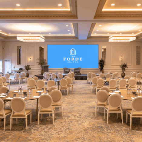 Elegant hotel conference room set with rounded tables and chairs, ready for an event.