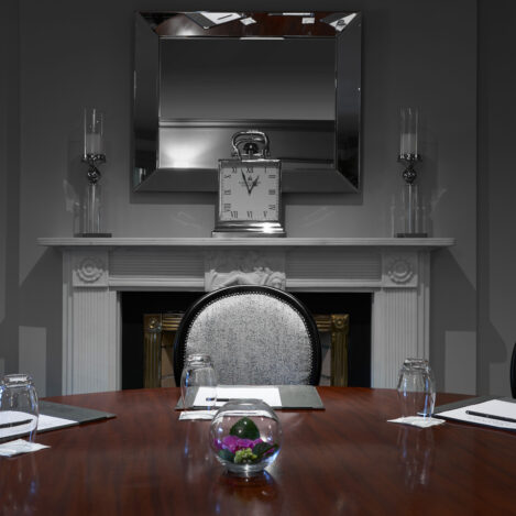 Elegant meeting room with silver decor, a fireplace, and a polished wood table set for guests.