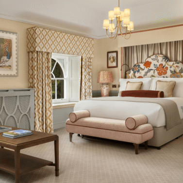 Elegant hotel room with a cosy bed and seating area. Large windows offer scenic outdoor views.