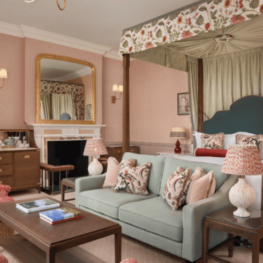 Elegant hotel room with a canopy bed and cosy seating area in charming décor.