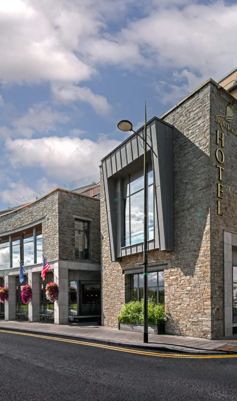 Modern hotel exterior with stone facade under a blue sky, inviting and welcoming atmosphere.